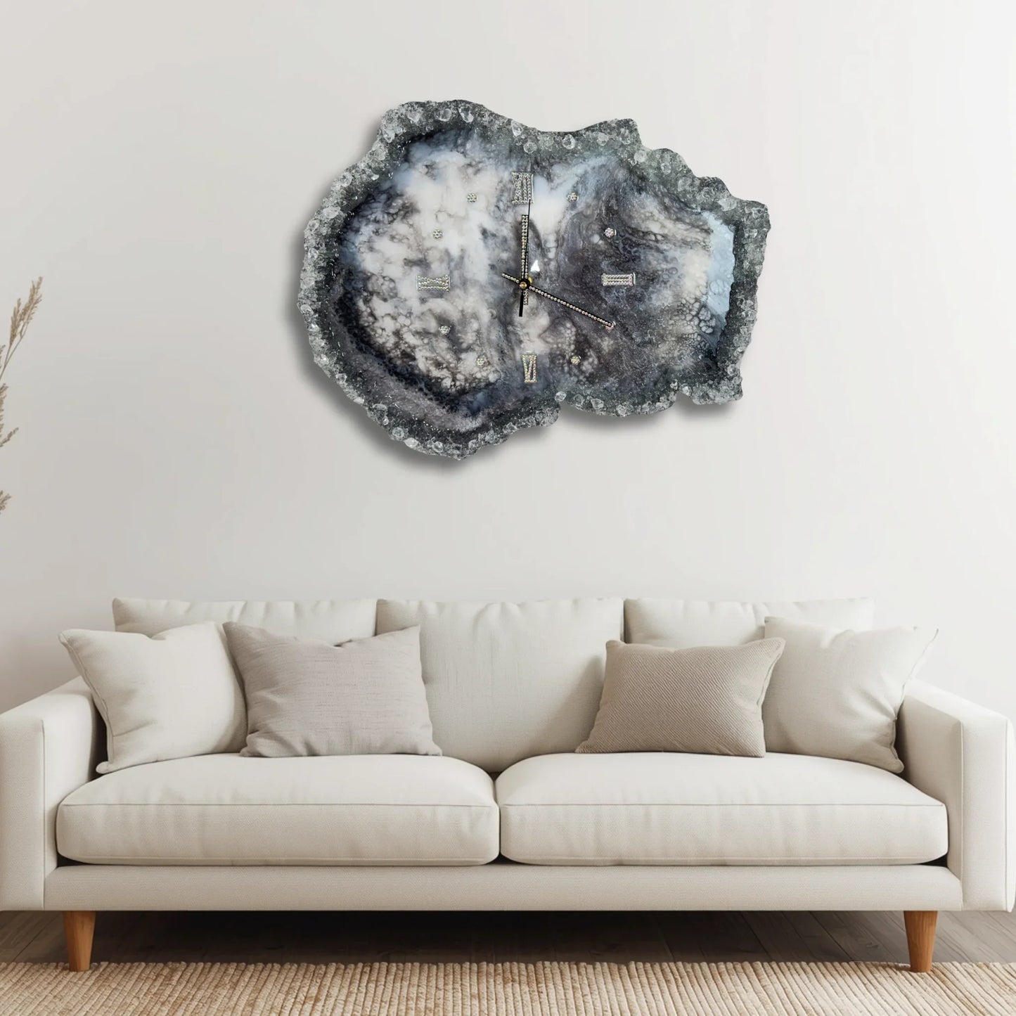 Moderne Geoden-Wanduhr aus Epoxidharz als stilvolles Dekorelement über einem weißen Sofa in einem hellen, minimalistischen Wohnzimmer.