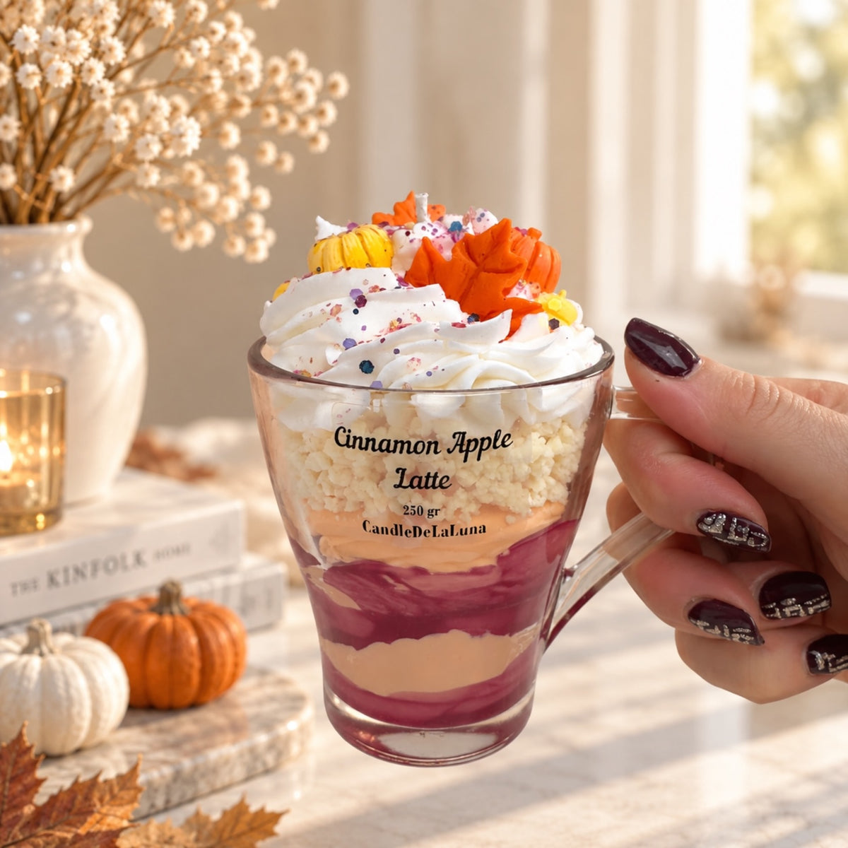 Apfel Zimt Latte Dessertkerze in der Hand – Größenvergleich, bordeaux-orange Wachsschichten mit Sahne und Herbstblatt-Deko, handgefertigte Duftkerze von DaarArt
