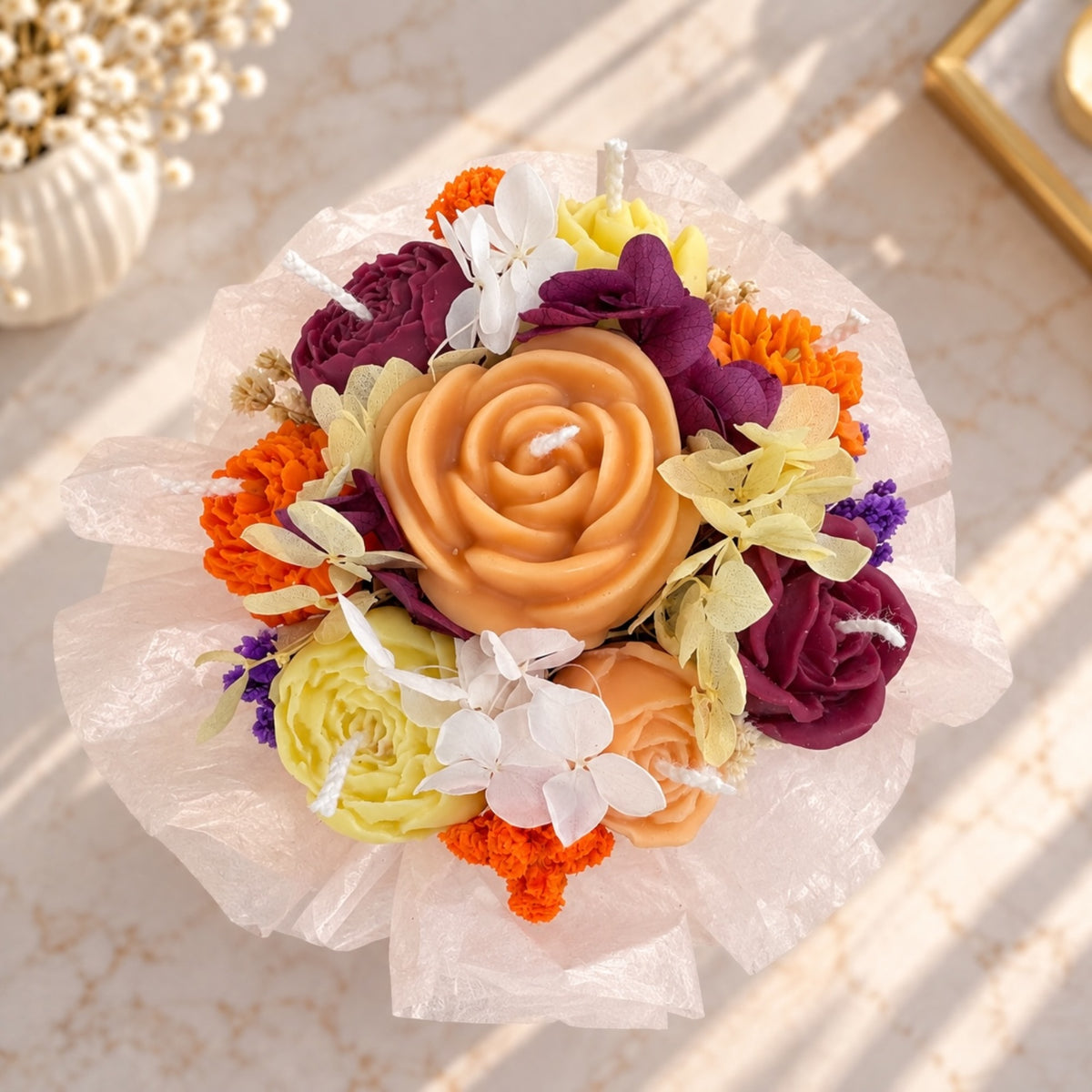 Kleines Kerzenbouquet in weißer Box mit goldenem Etikett auf einem Marmortisch
