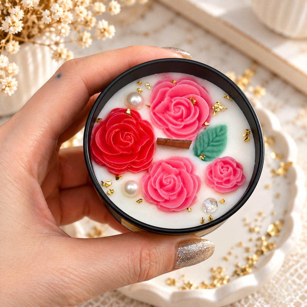 Blumenkerze in schwarzer Dose mit roten und rosa Rosenmotiven und grünem Blatt
