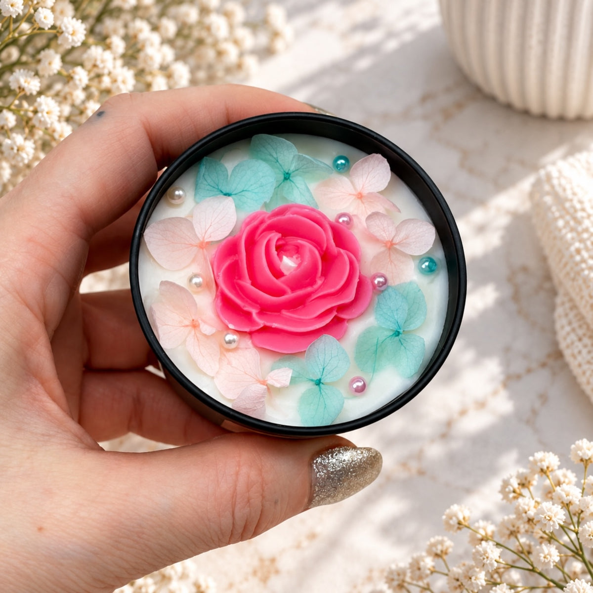 Blumenkerze in schwarzer Dose mit pinkem Rosenmotiv, hellrosa und türkisfarbenen Blüten und kleinen Perlen
