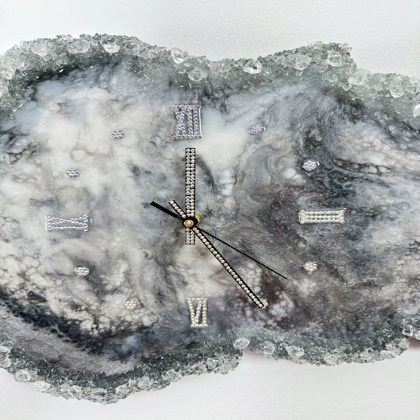 Detailaufnahme einer Kunstharz-Wanduhr mit funkelnden Kristallen, Strass-Ziffern und eleganten Zeigern auf einem grau-weißen Marmoreffekt-Hintergrund."Что выделено в описании: