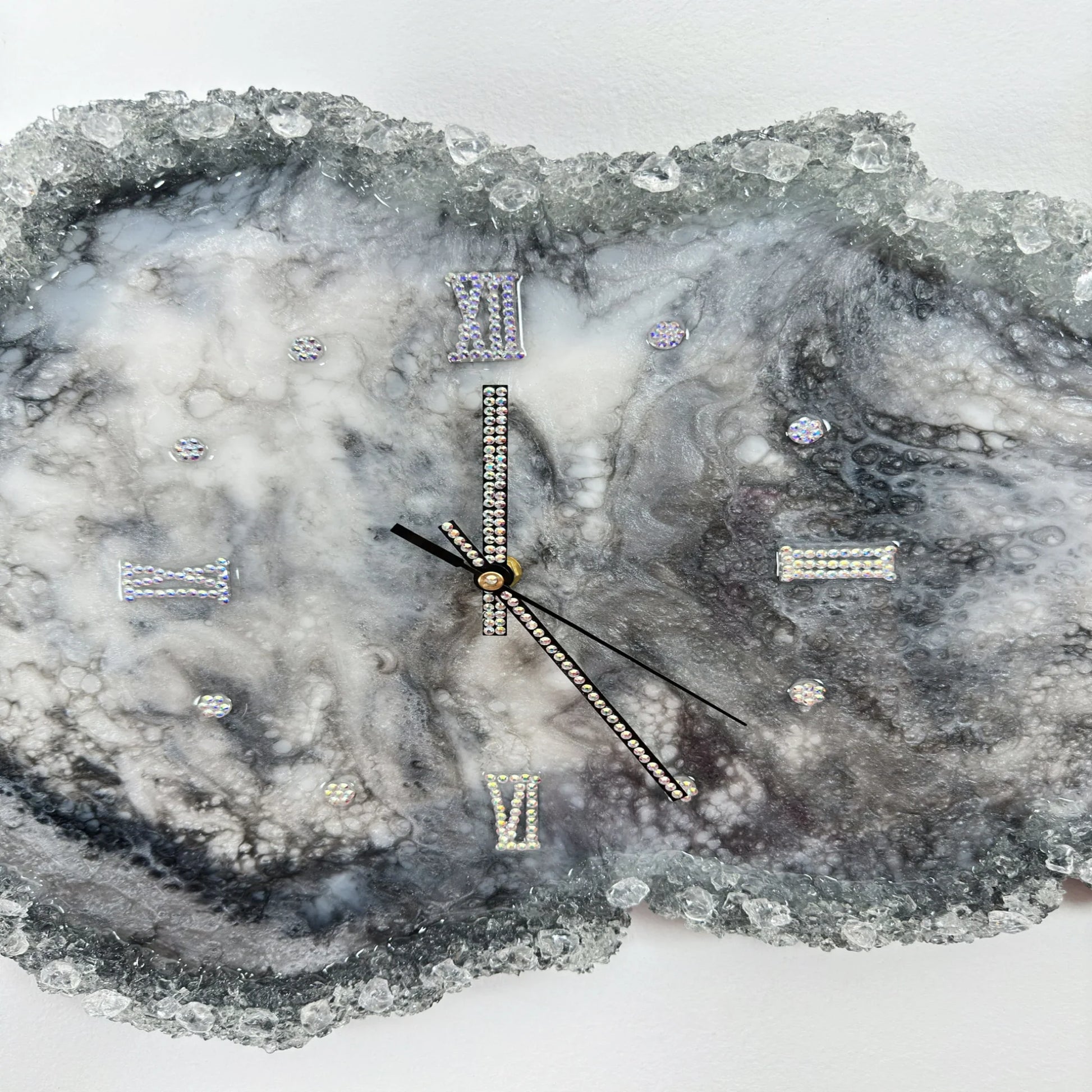 Detailaufnahme einer Kunstharz-Wanduhr mit funkelnden Kristallen, Strass-Ziffern und eleganten Zeigern auf einem grau-weißen Marmoreffekt-Hintergrund."Что выделено в описании: