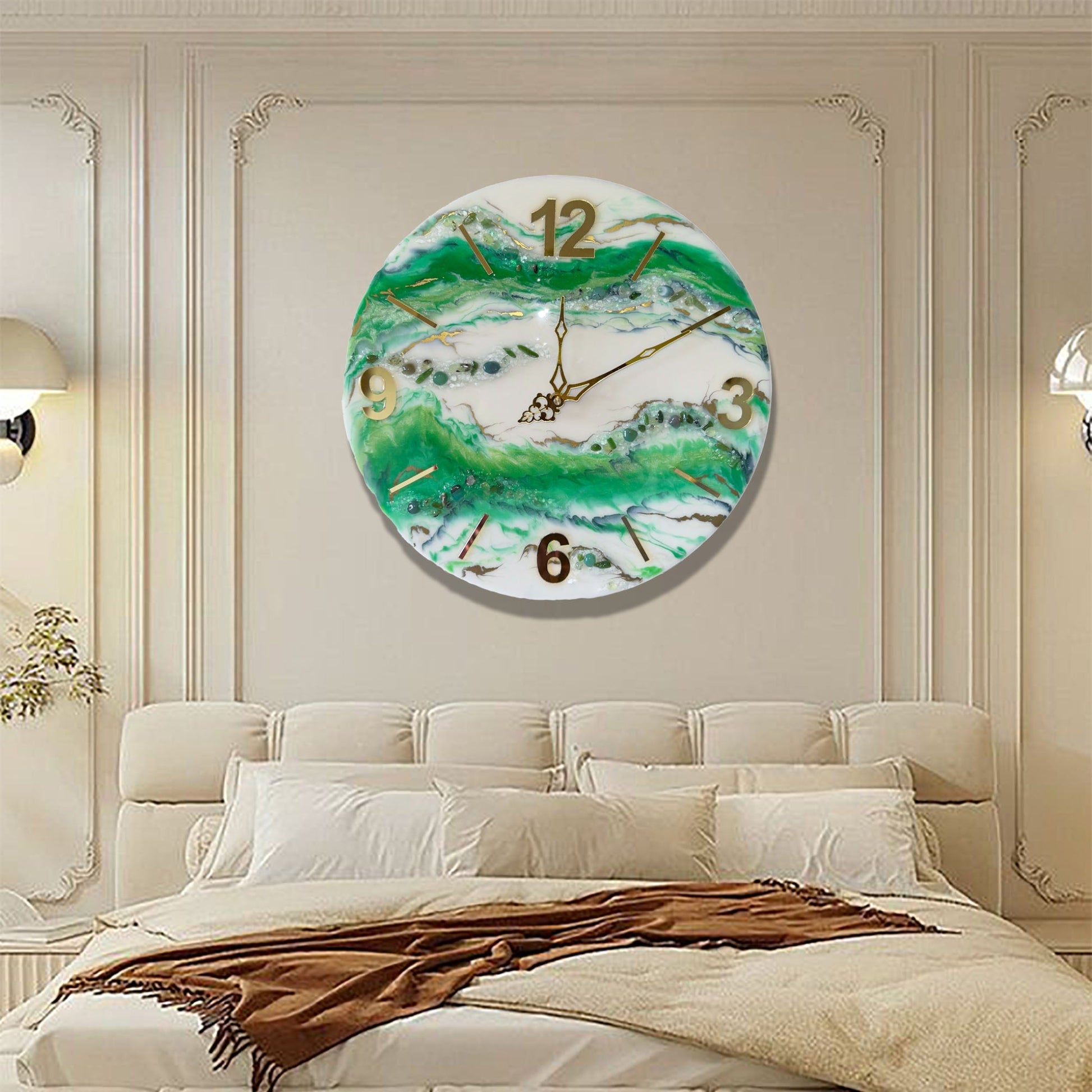 Eine runde Wanduhr aus Epoxidharz im Geoden-Stil mit grünen, weißen und goldenen Mustern, aufgehängt an einer klassischen beige Wand mit Zierleisten direkt über einem großen, eleganten Bett in hellen Brauntönen.