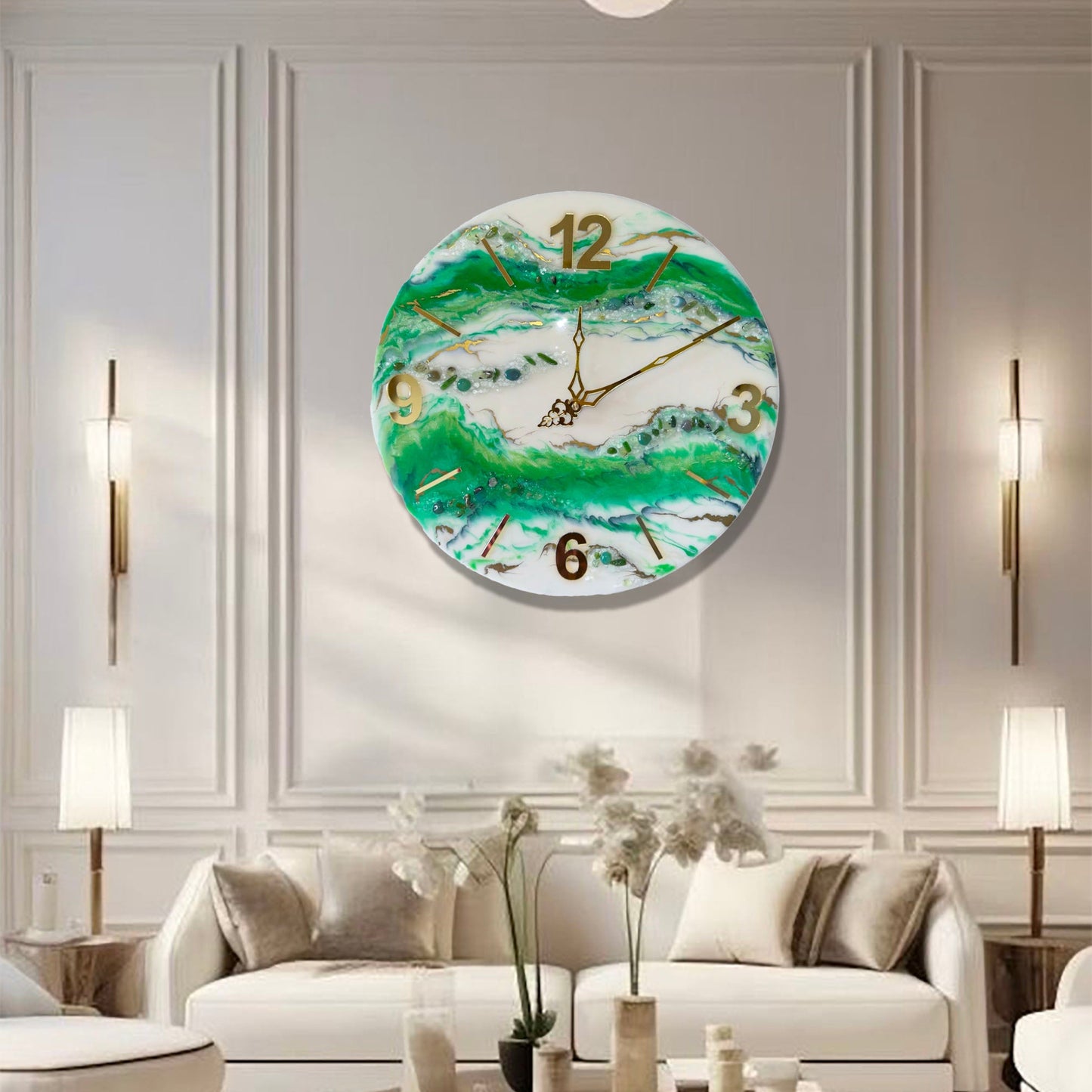 Eine runde Wanduhr aus Epoxidharz im Geoden-Stil mit grünen, weißen und goldenen Mustern, aufgehängt an einer klassischen hellen Wand mit Zierleisten über einem weißen Sofa, flankiert von zwei Stehlampen und Wandleuchten.