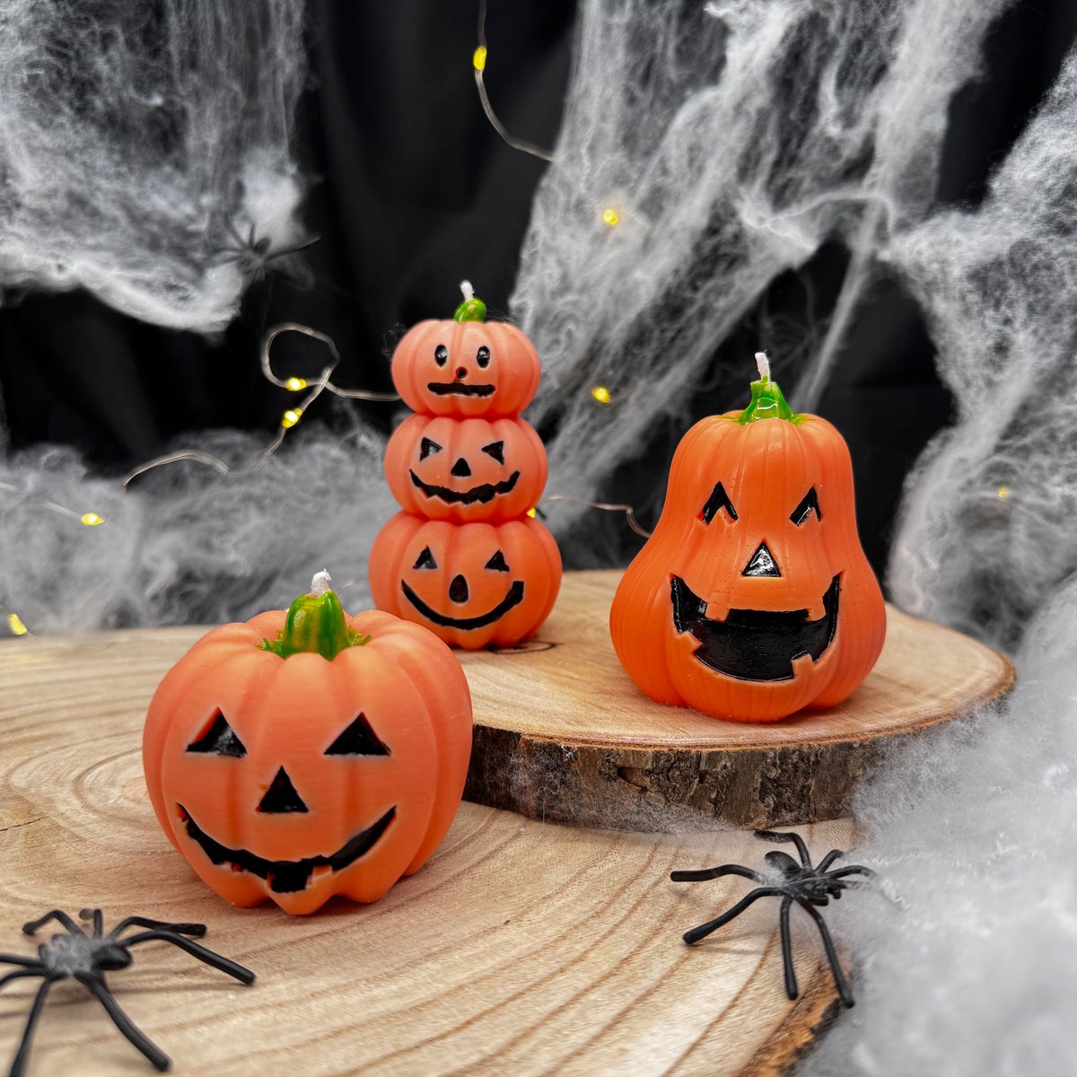 Drei orangefarbene Kürbiskerzen mit unterschiedlichen Gesichtern als Halloween-Dekoration
