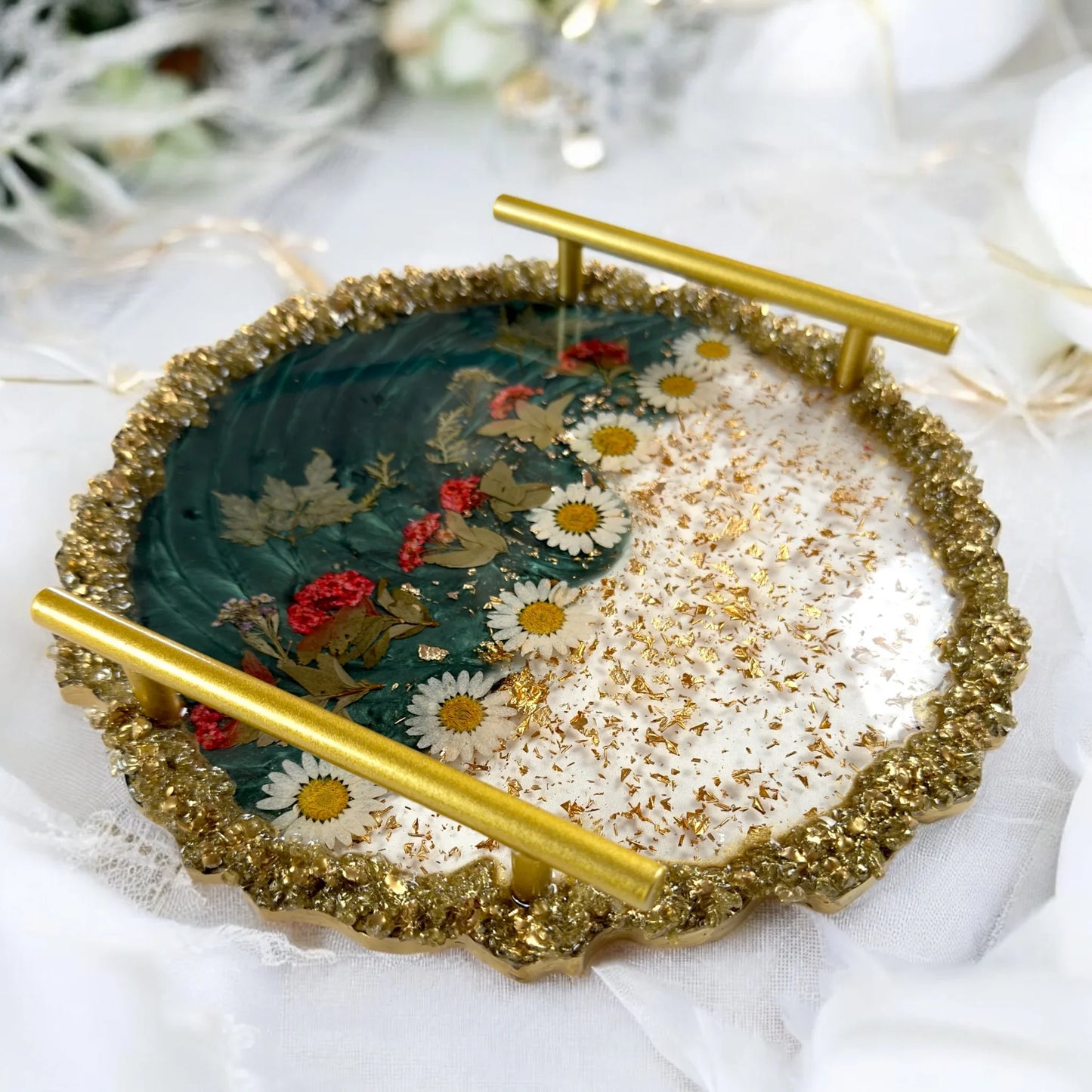 Handgefertigtes Tablett aus Resin in Grün-Gold Optik mit zwei stabilen Metallgriffen und eingegossenen Gänseblümchen auf hellem Hintergrund.
