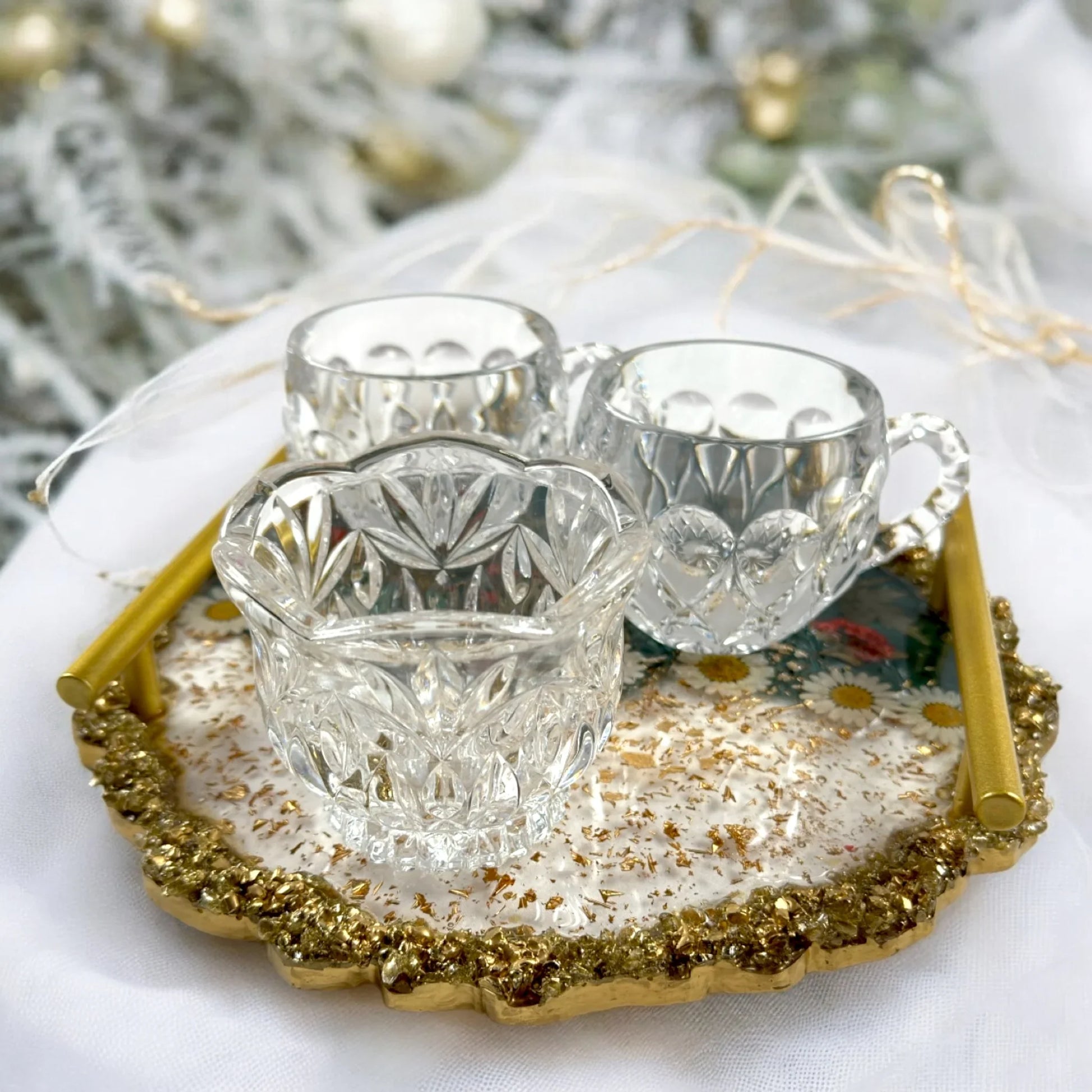 Rundes Epoxidharz Tablett mit Goldgriffen serviert mit gläsernen Tassen und einer Schale auf einer weißen Festtafel mit weihnachtlicher Dekoration.