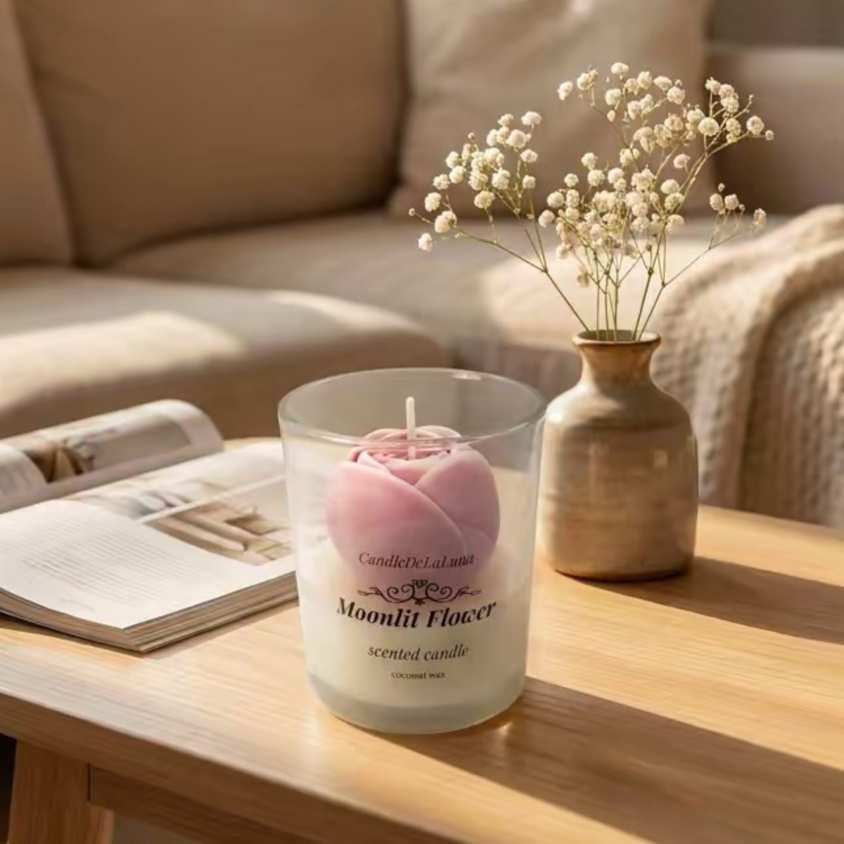 Rosa Rosenkerze im Glas auf einem Holztisch im Wohnzimmer neben Vase mit Schleierkraut und Zeitschrift
