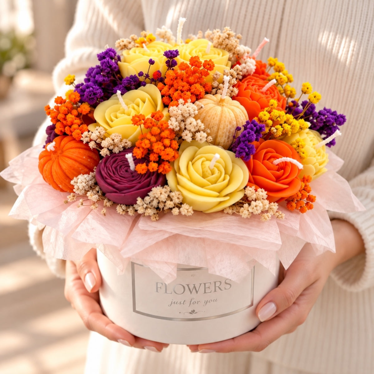 Hände halten ein Kerzenbouquet in einer weißen Blumenbox mit Aufschrift „Flowers just for you“
